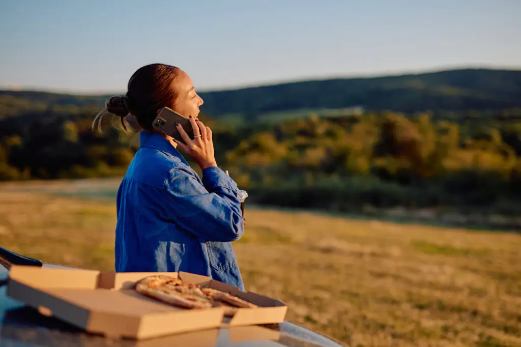 Kobieta korzysta ze smartfona podczas podróży. Jest zadowolona, bo&nbsp;kupiła pakiet internetowy i&nbsp;nie martwi się o&nbsp;zużycie danych.